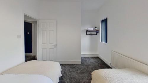 two beds in a room with white walls at Elegant 2 Bed House Near City Centre in Manchester