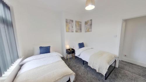 three beds in a room with white walls at Elegant 2 Bed House Near City Centre in Manchester
