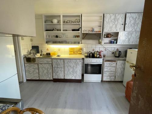 una cocina con armarios blancos y electrodomésticos blancos en gms service, en Lorenskog