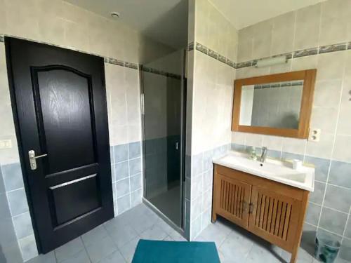 La salle de bains est pourvue d'un lavabo et d'une porte noire. dans l'établissement Maison spacieuse avec piscine, à Hinx