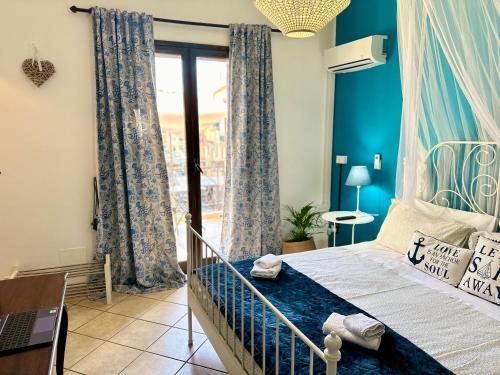 Schlafzimmer mit einem Bett mit blauen Wänden und einem Fenster in der Unterkunft Case Vanella Grande aspra bagheria in Bagheria