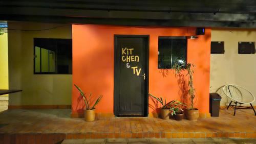 un edificio arancione con una porta nera e piante di Casa Alamanda - Posada Urbana a Ciudad del Este