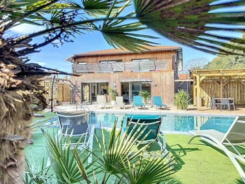 une maison avec une piscine et des chaises dans l'établissement La Villa Vinsou avec piscine proche golf et océan, à Seignosse