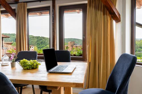 a laptop on a wooden table in a room with windows at Bobevata guest house - Floor 2 - Stunning view Old town in Veliko Tŭrnovo