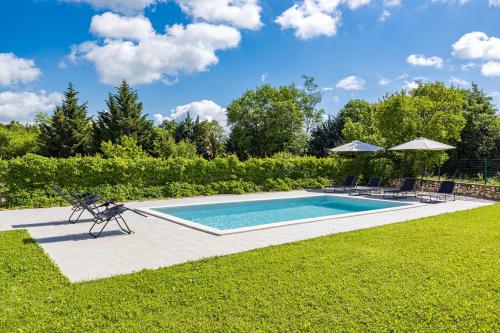 una piscina en un patio con sillas y sombrillas en Old Stone Villa Katarina, en Nedeščina