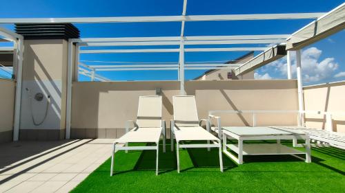 2 chaises blanches et une table sur un balcon dans l'établissement Villa Amalia Eco, à Torrevieja
