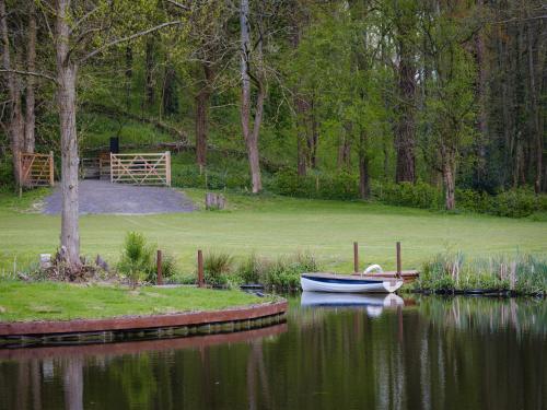 a small boat sitting in the water next to a yard at 5 Bedroom Lake House in a nature reserve in Devizes