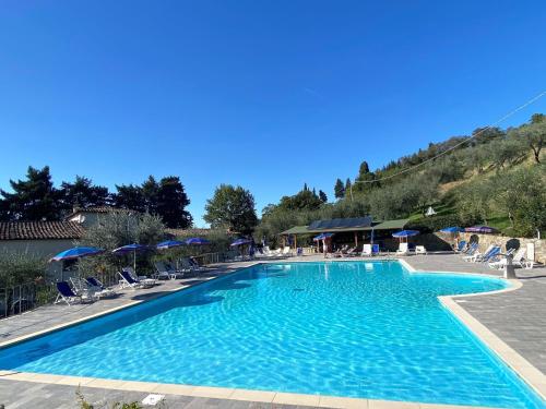 una gran piscina azul con sillas y sombrillas en Apartment Villa Grassina-4 by Interhome, en Pelago