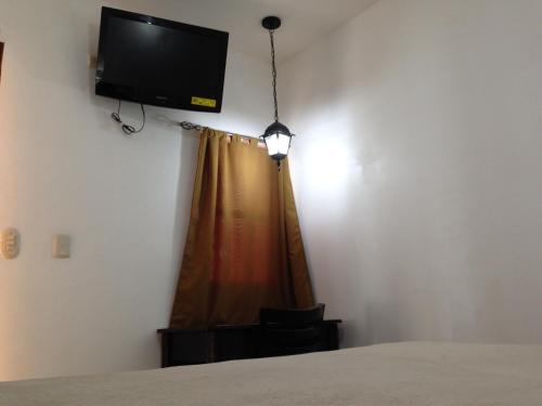a bedroom with a bed and a television on the wall at Hotel Mozonte in Managua