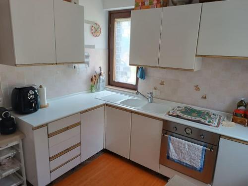 Una cocina con gabinetes blancos y un fregadero y una ventana. en Casa degli uccellini - Cerreto di Spoleto, en Cerreto di Spoleto