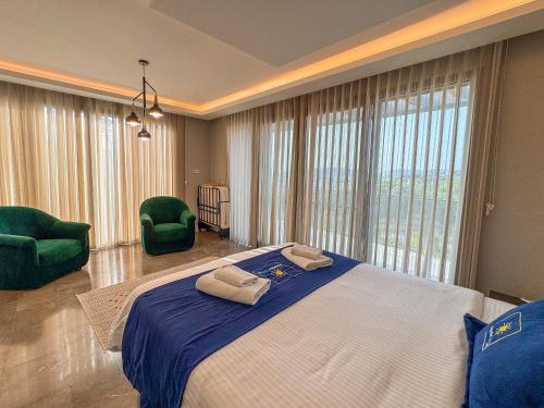 a bedroom with a large bed and two green chairs at Villa Elite in Kusadası