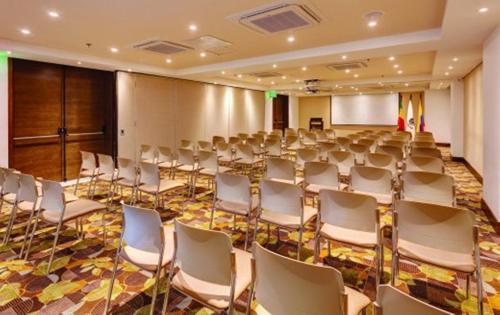 a room with rows of white chairs and a screen at Hotel Estelar Yopal in Yopal
