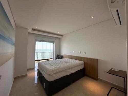 um quarto com uma cama e uma grande janela em Condomínio Costa Esmeralda no Guarujá