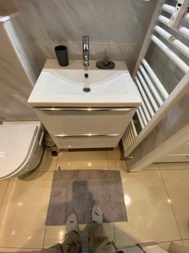 une personne se tient debout dans une salle de bain avec un lavabo dans l'établissement Studio bord de mer, à Cannes