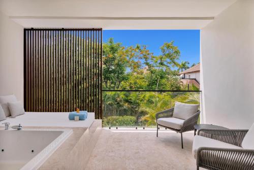 a bathroom with a tub and a chair and a large window at Live Aqua Punta Cana - All Inclusive - Adults Only in Punta Cana