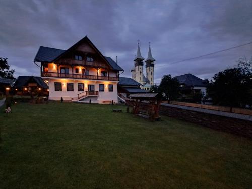 a house with lights on in a yard at night at Pensiunea Maramu in Breb