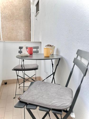 a small table with a chair and a table with two cups at FiloXenia by the Sea in Agios Nikolaos
