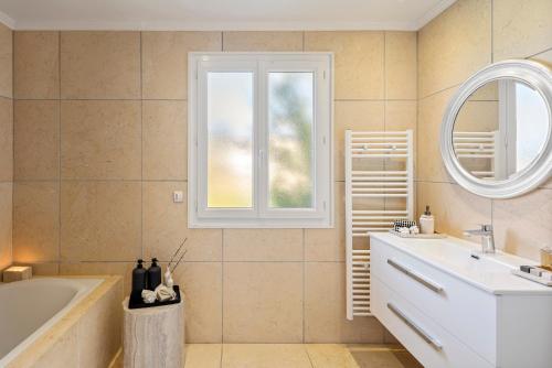 une salle de bain avec une baignoire, un lavabo et un miroir dans l'établissement Villas Raphaël, aux Issambres