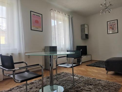 sala de estar con mesa de cristal y sillas en Eisenerzer Apartments - Radmeisterhaus, en Eisenerz