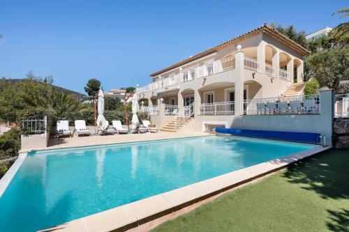 une grande maison avec une piscine devant dans l'établissement Villas Raphaël, aux Issambres