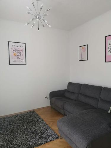 a living room with a gray couch and a chandelier at Eisenerzer Apartments - Radmeisterhaus in Eisenerz