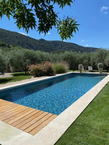 - une piscine avec une terrasse en bois à côté d'une cour dans l'établissement Le Champ des Oliviers, à Oppède