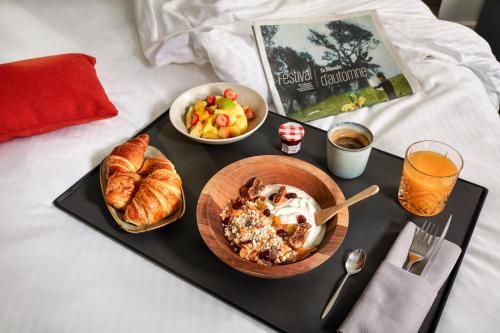 a tray of food with bread and croissants on a bed at Novotel Paris Créteil Le Lac in Créteil