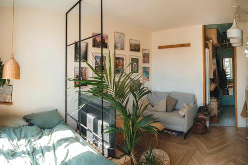 un salon avec un canapé et une plante dans l'établissement Appartement Studio Paris La Défense, à Suresnes