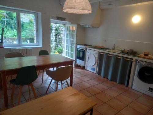 une cuisine avec une table et des chaises ainsi qu'une buanderie dans l'établissement Maison médiévale avec jardin dans charmant village, à Vers