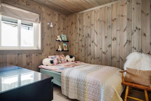 a bedroom with wooden walls and a bed and a window at Voss Resort self-service apartments in Skulestadmo