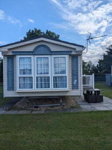 a small house with a large window in a yard at i7 Millfields 6 Berth Luxury Caravan DG & GCH Familys Only And Lead Person Must Be Over 30 in Ingoldmells