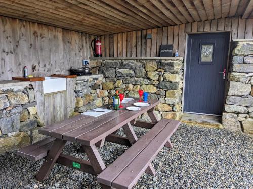 una mesa de picnic de madera en una cabaña con puerta en Blackhouse Bothies, en Balallan