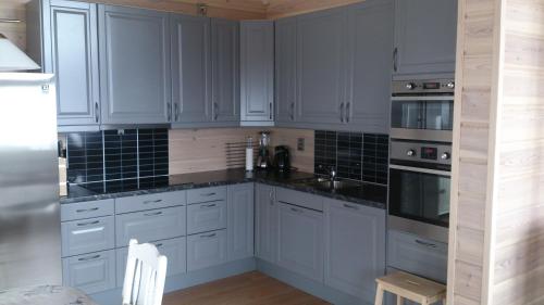 a kitchen with white cabinets and black counter tops at Voss Resort self-service apartments in Skulestadmo