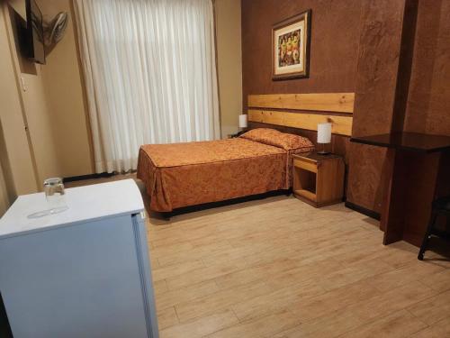 a hotel room with a bed and a refrigerator at Hotel El Brujo Centro Histórico in Trujillo