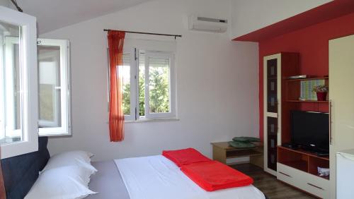 a bedroom with a bed and a tv and two windows at Apartments Luna in Sukošan