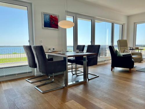 a dining room with a table and chairs and windows at Ferienwohnung eastside App 3 Olpenitz in Olpenitz