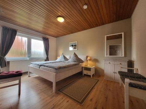 a bedroom with a bed with a wooden ceiling at Haus Ruhewinkel, Bungalow 1 in Alkersum