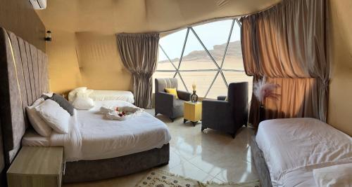 Cette chambre comprend deux lits et une grande fenêtre. dans l'établissement Golden Gate Luxury Camp, à Wadi Rum