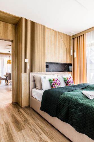 a bedroom with a large bed with a green blanket at Apartamenty Krokusowa Dolina in Kościelisko