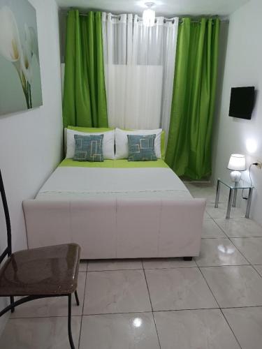 a white bed in a room with green curtains at Hill Veiw Rooms in St Mary