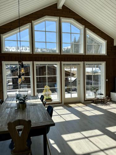 a large room with a wooden table and windows at Voss Resort self-service apartments in Skulestadmo