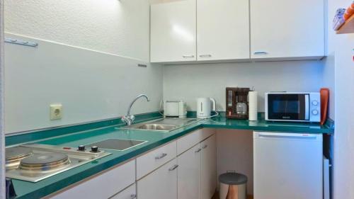 eine Küche mit einer Theke mit einer Mikrowelle und einer Spüle in der Unterkunft Leuchtfeuer in Wendtorf