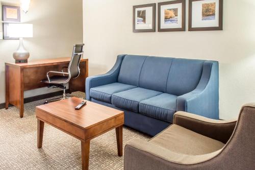 a living room with a blue couch and a table at Comfort Suites Near Potomac Mills in Woodbridge