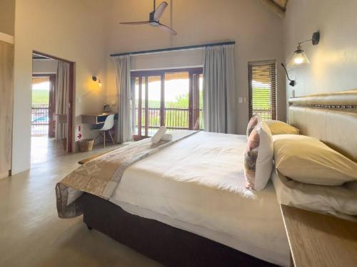 a large bedroom with a large bed and a balcony at Kanaan, Mabalingwe in Mabula