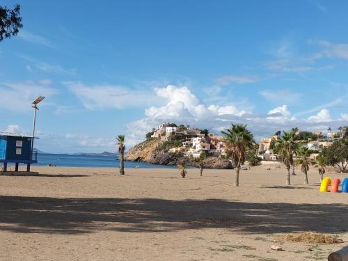 a sandy beach with palm trees and a resort at Bol01 - Modern 2 bedroom apartment in Bolnuevo in Bolnuevo