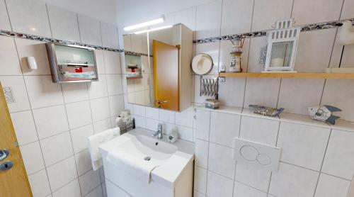 a white bathroom with a sink and a mirror at Appartement-Service-Laboe Haus Seewind in Laboe