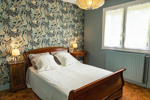 a bedroom with a bed with a blue and green wallpaper at Maison de charme au bord du lac à Ouzouer-sur-Trézée in Ouzouer-sur-Trézée