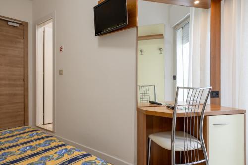 a room with a bed and a desk with a chair at Hotel Continental in Caorle