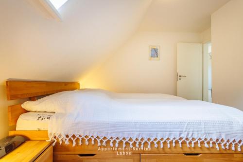 a bedroom with a white bed in a attic at Kapitänshaus Fewo Seemann Budle in Laboe