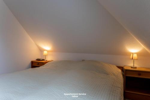 a bedroom with a bed and two lamps on night stands at Kapitänshaus W13 in Laboe